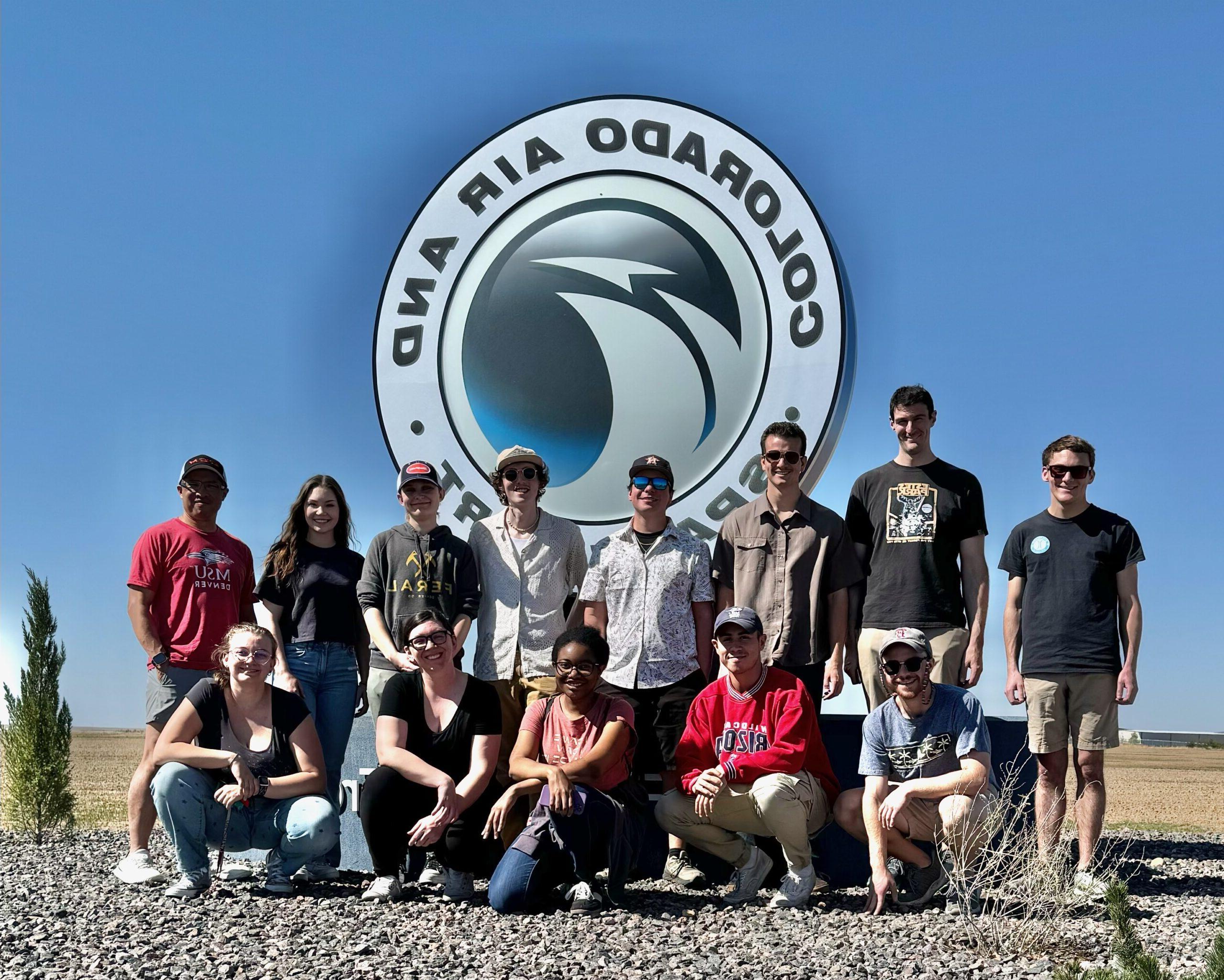 Students and professor pose for a picture in front of the radar site sign.